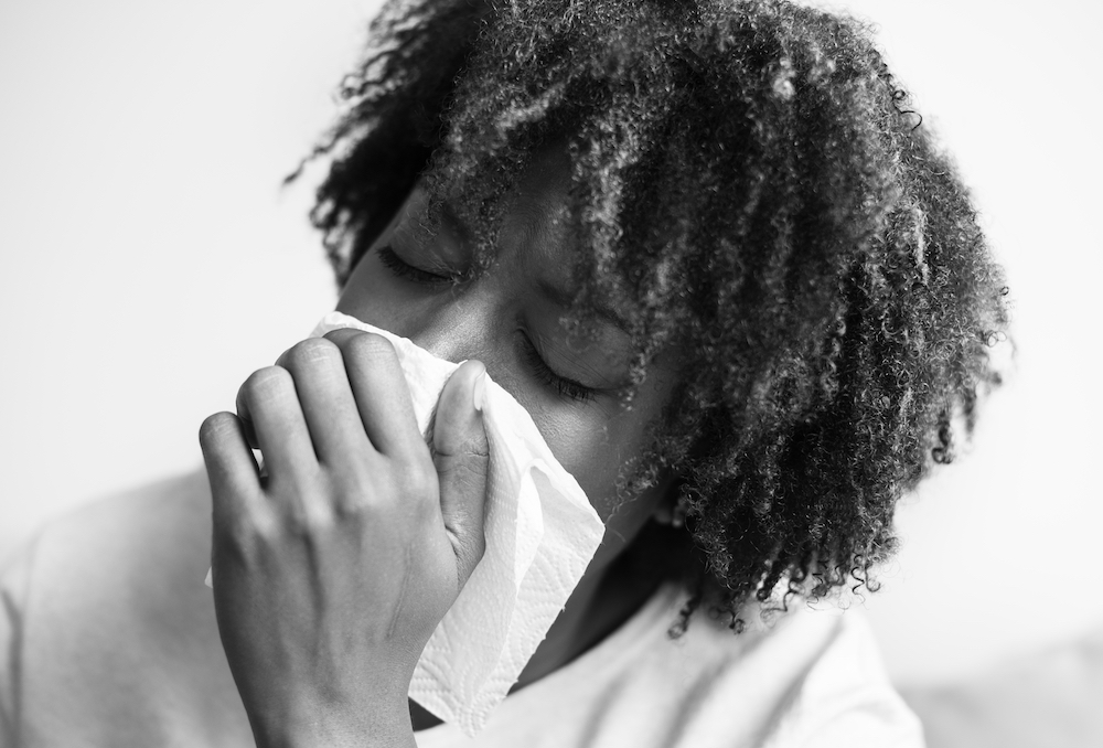 woman holding tissue over mouth while coughing